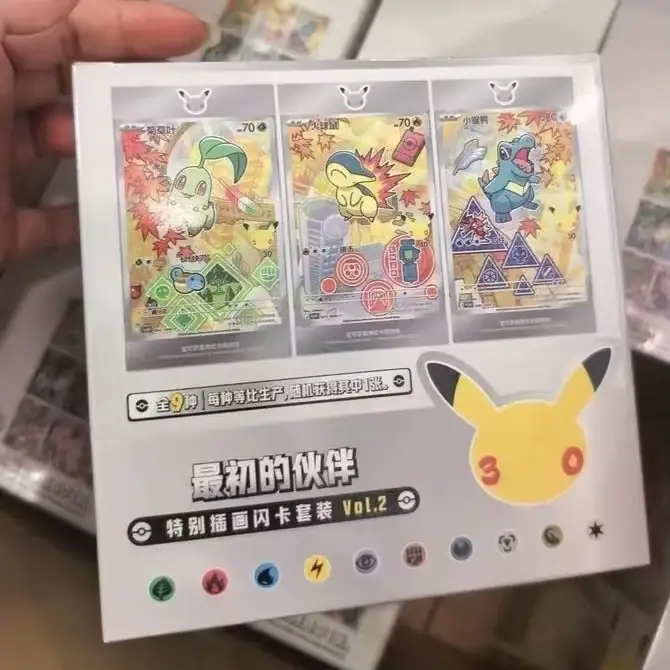 Handheld white Vol.2 package with three illustrated card panels and Pikachu anniversary graphic, not a full eight-box display